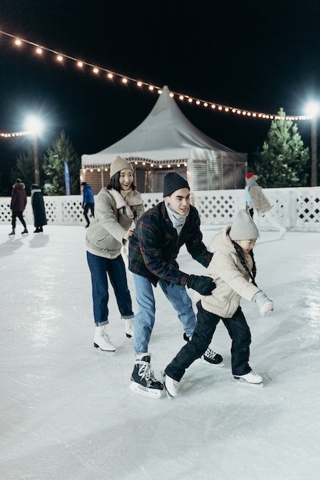 Family members skating on an outdoor rink for Christmas card photo ideas