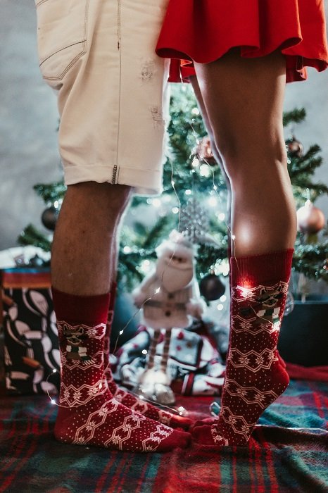 Christmas couple photoshoot inspiration: the woman half of this couple stands on her tippy toes to kiss her boyfriend