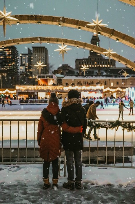 a couple photographed looking at the holiday decorated ice skating rink 