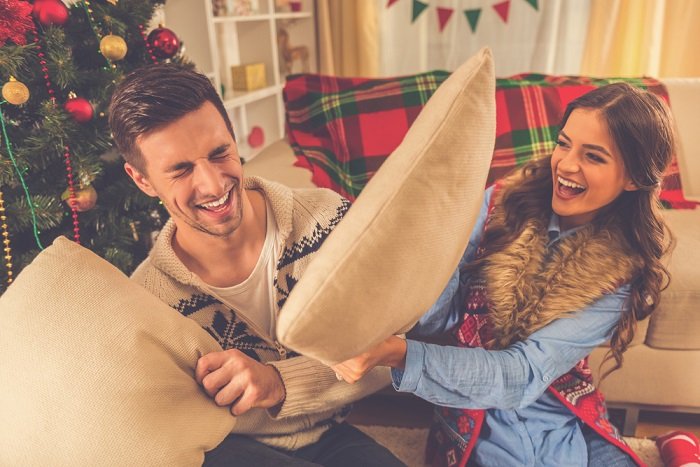 Christmas couple photoshoot ideas: a couple enjoying some laughter during a pillow fight 