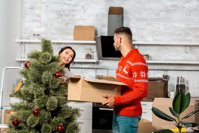 Christmas couple photoshoot tips: a couple unpacks Christmas tree ornaments to hang on the tree