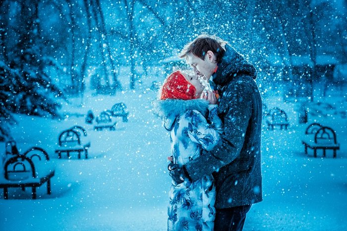 Christmas couple photoshoot inspiration: a couple kisses as snow falls around them 