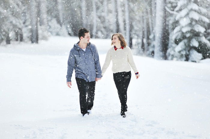 Tips for a Christmas couple photoshoot: a couple walks hand in hand in the snow