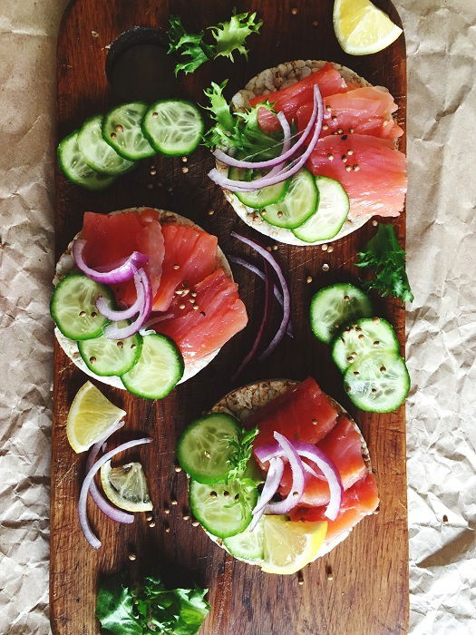 Rice cakes and toppings displayed on a wooden board used as a food photography prop