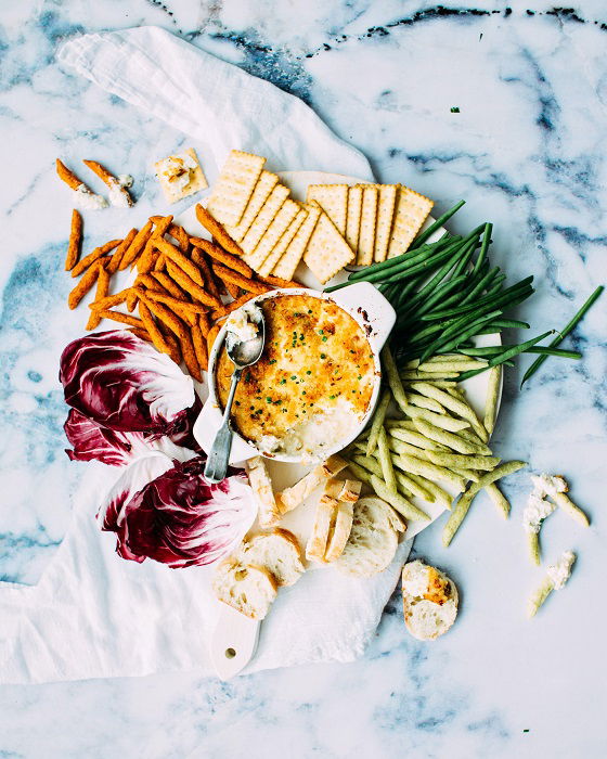 Assorted finger food and dip on a marble backdrop used as food photography prop