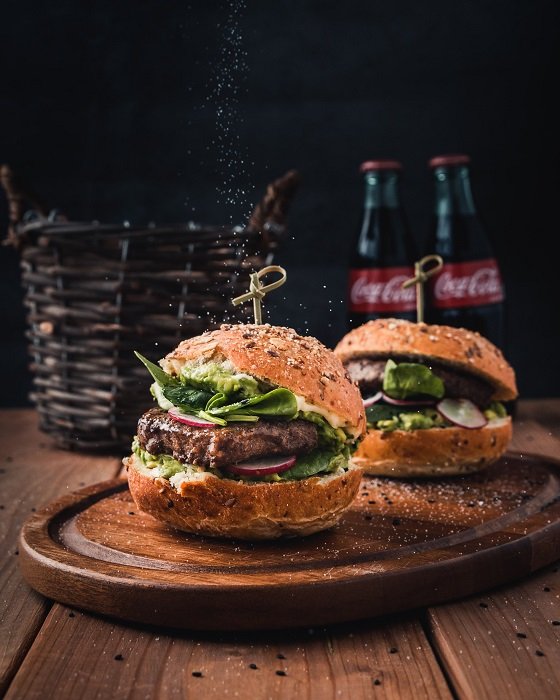 Two burgers and buns with toothpicks used as food photography props to hold them in place