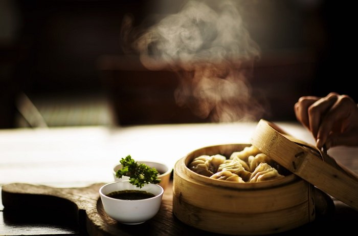 Food photography props: Dip in a small bowl and dumplings in a bamboo container with steam rising from them