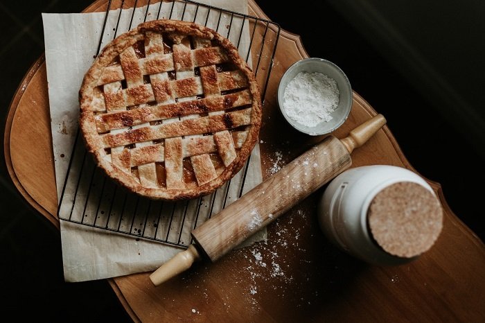 A baked pie with food photography props of on an oven rack parchment paper a rolling pin and flour