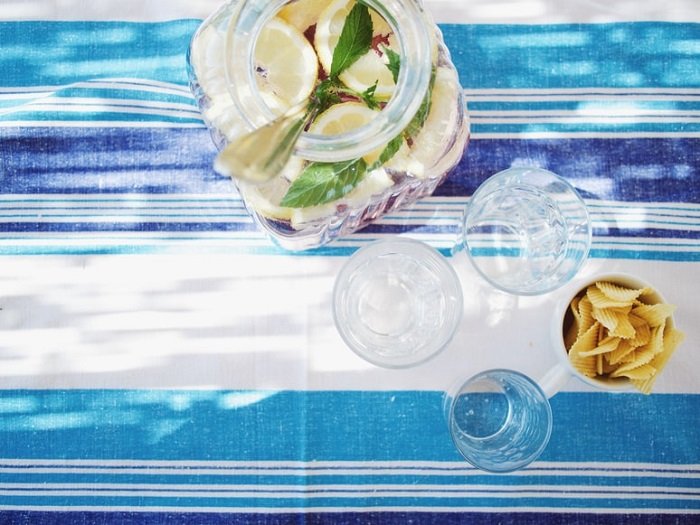 Lemon water and glasses shot from above on a striped food photography prop tablecloth