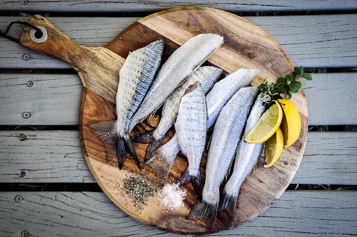 Food Photography tips: flat lay photo of prepped sardines resting on a wooden board with lemon garnish