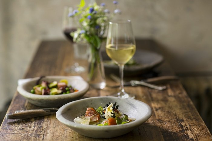 Food Photography tips: a shallow depth of field shot captures two bowls and two glasses of wine on a wooden table