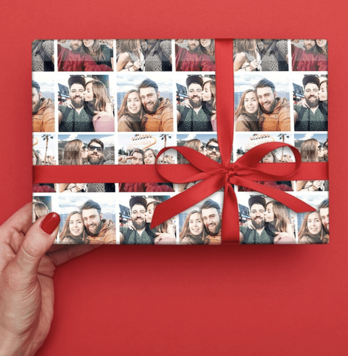 A red bow tied around custom wrapping paper as a photo gift idea