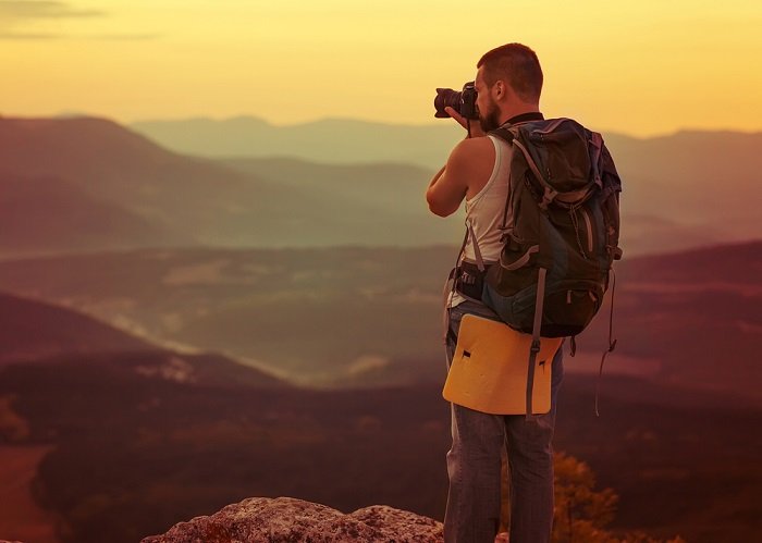 a photographer taking a photo of a sunset over a mountain range