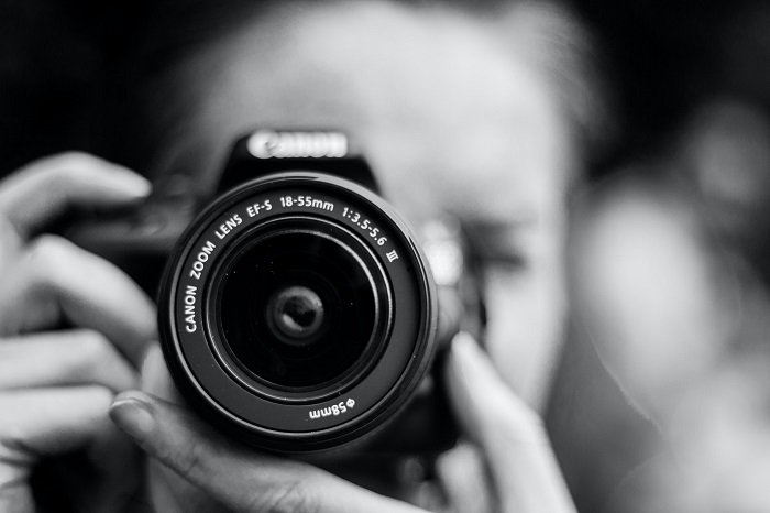 a shallow depth of field black and white photo of a woman taking a photograph
