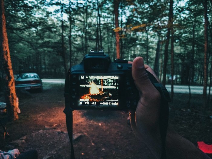 What is a Raw file: a photographer looks at his camera's settings as he takes a photo of a campfire