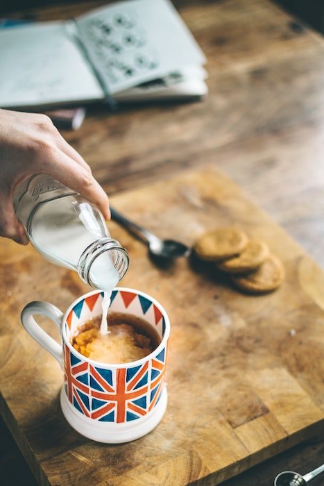 Milk being poured into a coffee mug with a UK flag on it used as a food photography prop