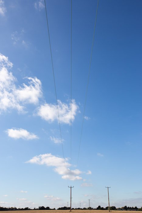 canon lens shot of a field with electrical lines 