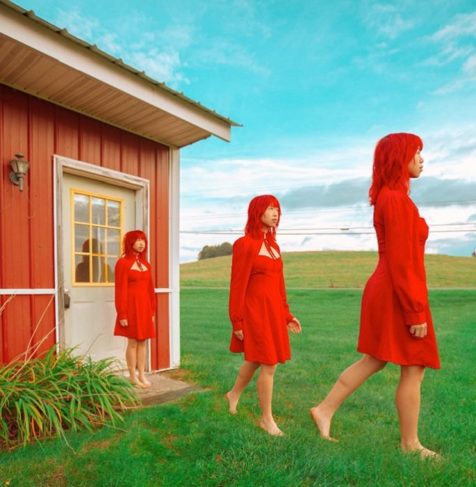 a composite image of a duplicated woman in a red dress walking into a field