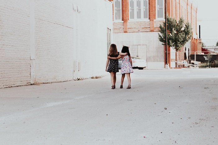two young girls walking arm in arm down an alley as a sister photoshoot idea