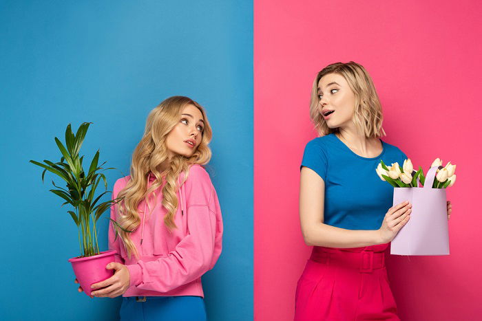 Two girls holding plants in a studio a sisters photoshoot idea