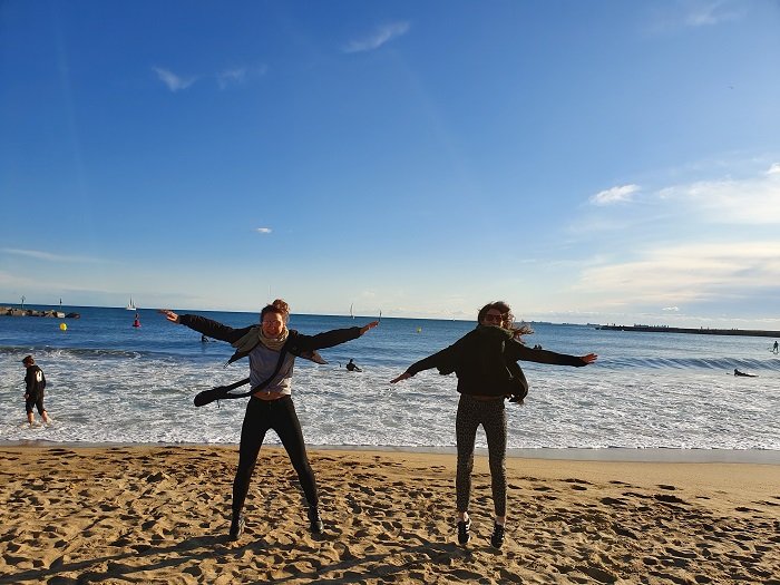 two girls doing star jumps on a beach a sisters photoshoot idea