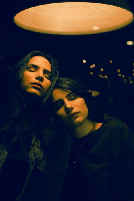 sister photoshoot ideas: Two girls under a lamp in a moody setting