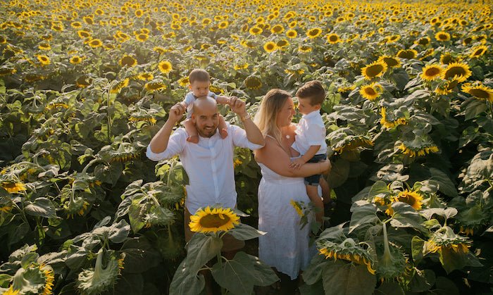 Four members of a family in a sunflower field in matching outfits