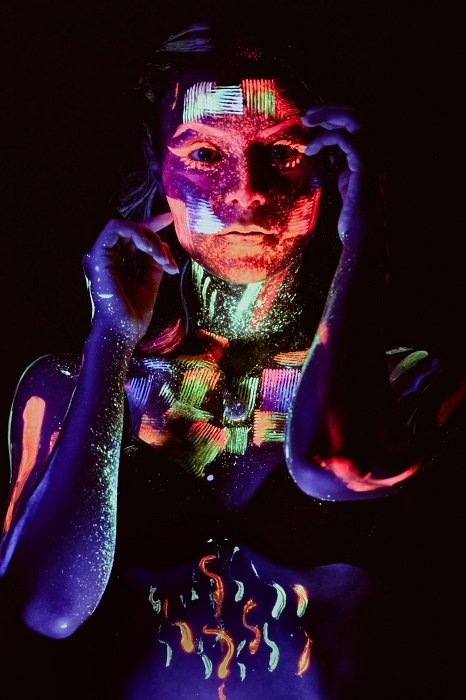 blacklight photograph of a woman covered in paint as an example of surreal photography