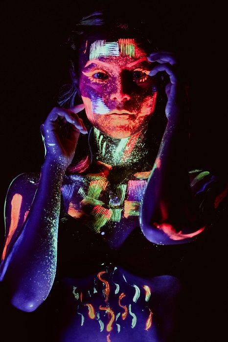 blacklight photograph of a woman covered in paint as an example of surreal photography