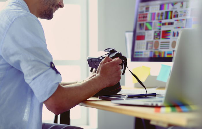 Photographer sitting in front of computer while looking at camera