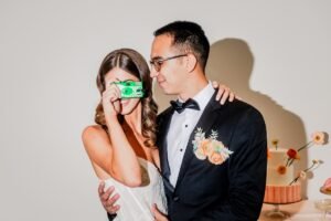 A groom looking at his bride taking a picture with an instant camera as one of our photography trends