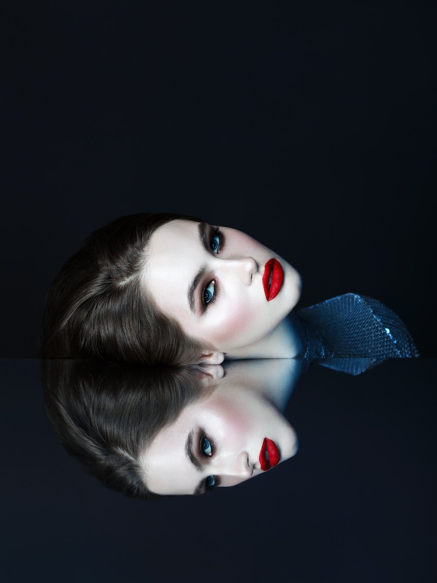 Hyperrealistic fashion headshot of.a woman's head and reflection in a glass table