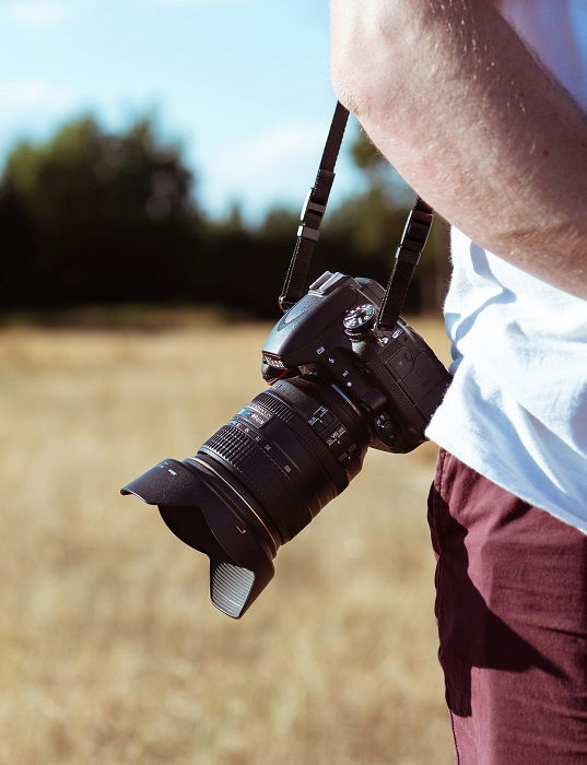 Alguém carregando uma Nikon DSLR com uma alça de ombro