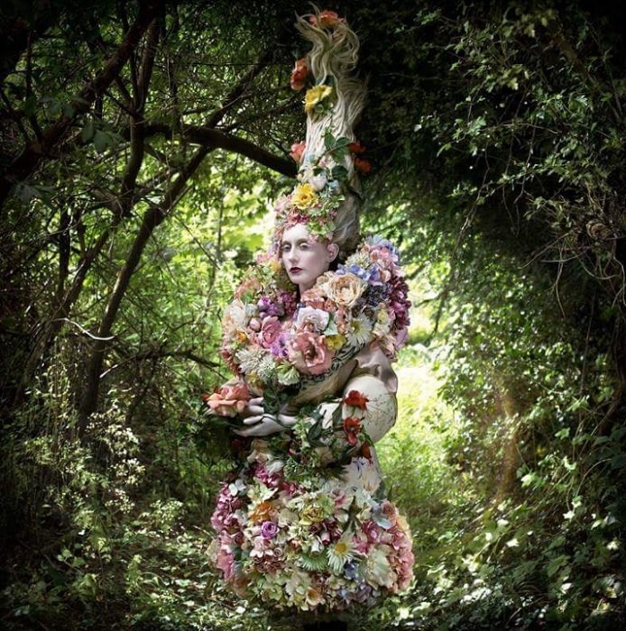 Mulher em uma elaborada roupa floral inspirada em um conto de fadas na floresta