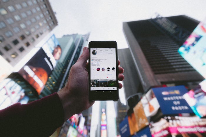 Pessoa segurando um telefone no ar exibindo uma biografia do Instagram