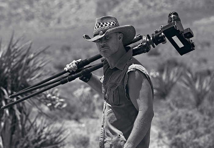 Photo of Peter Lik holding a tripod in the desert