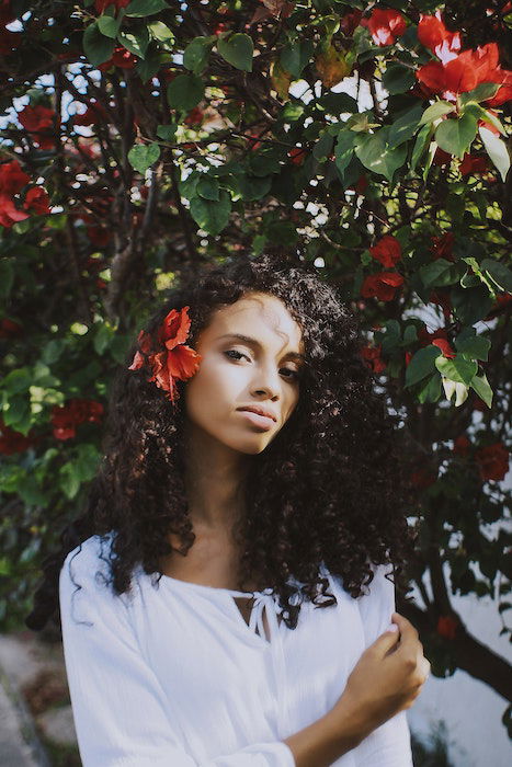 flower Portrait photography of a woman with a red flower behind her ear