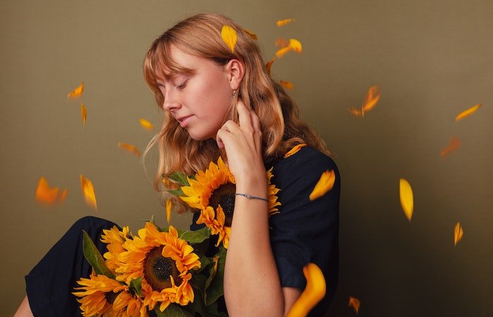 Portrait of a woman holding sunflowers with petals falling around her