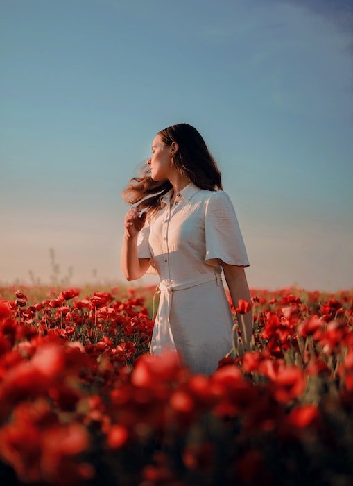 retrato com flores de uma mulher girando no meio de um campo vermelho