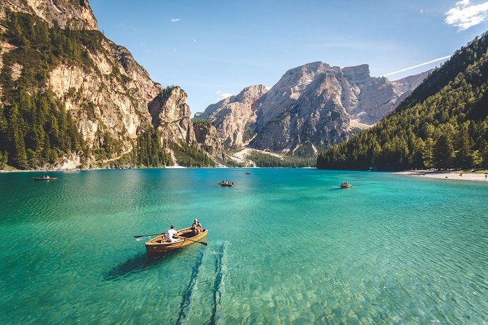 两个人划着小船在美丽的山脉前的湖上