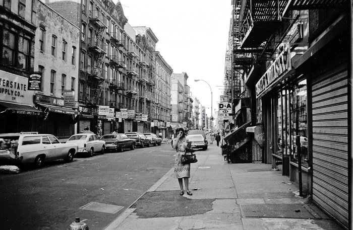 Black and white photo of woman walking down a city street