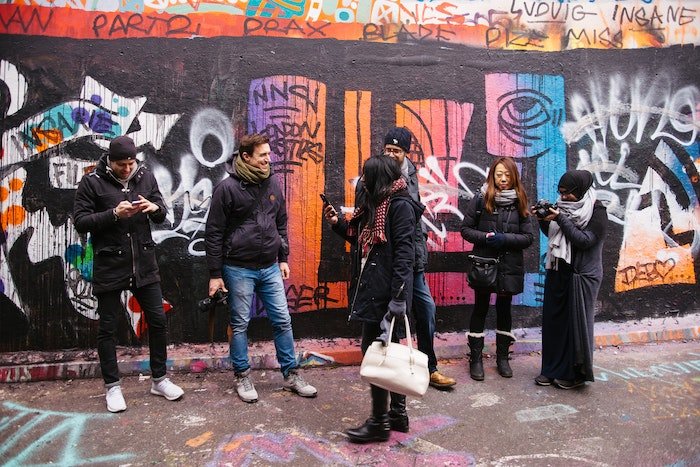 A group of photographers in a photo workshop standing in front of a graffiti wall