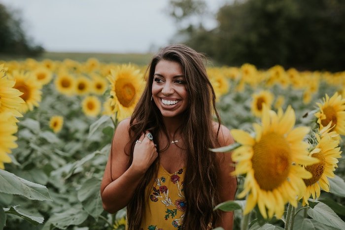 Portrait of a woman in a yellow, patterned dress in a sunflower field