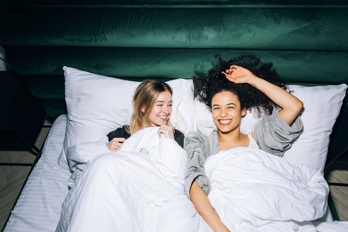 Two women laughing in bed