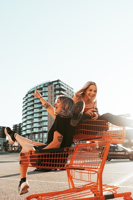 Two girls in a shopping cart posing for a best friend photoshoot