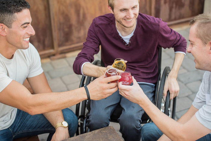 Three men clinking drinks outside a bar