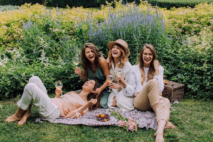 Four women having a picnic in a meadow for a best friend photoshoot