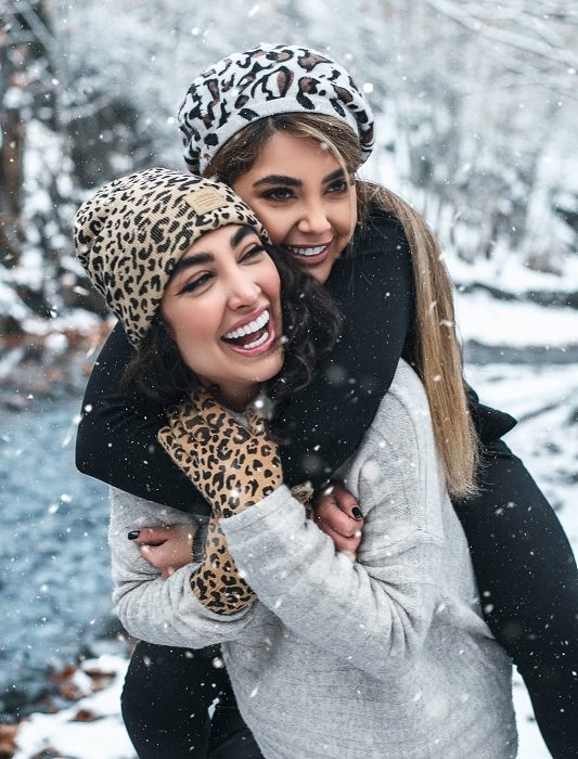 One girl giving another a piggyback in the snow