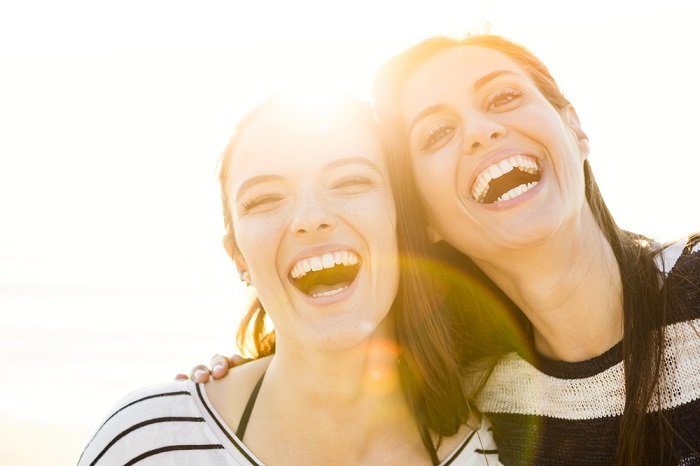 Two women laughing with sun glare