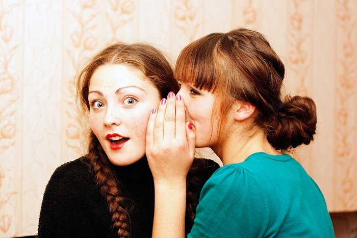 One woman whispering to another as an idea for a best friend photoshoot
